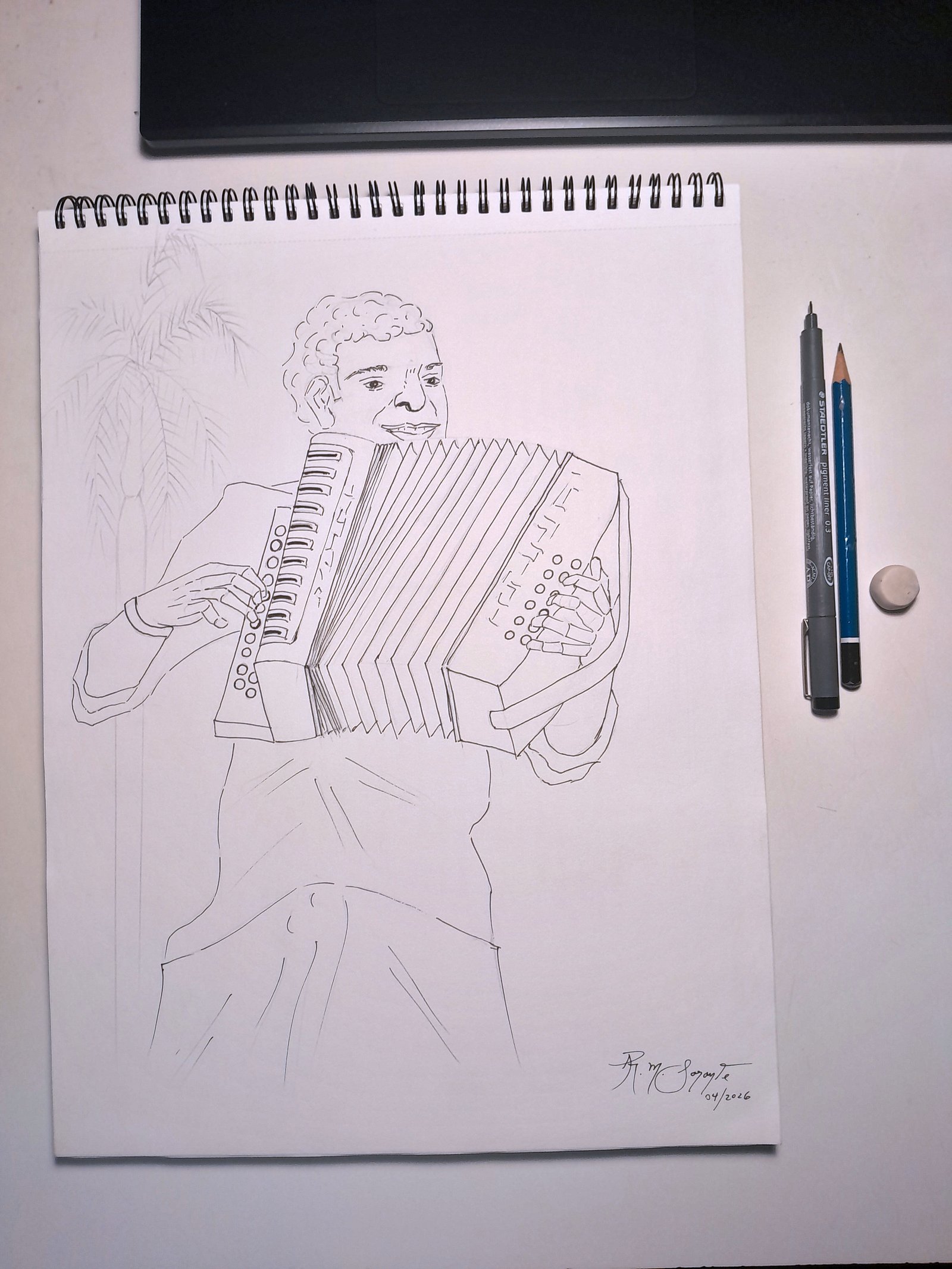 Detail of the creative process for Accordionist No. 2, showing a technical pen and graphite drawing on a spiral-bound sketchbook. The composition depicts a male accordionist playing the instrument, with carefully defined facial features, hands, buttons, keyboard, and bellows, while lightly sketched palm leaves remain visible in the background. A technical pen, graphite pencil, and eraser placed beside the drawing emphasize the hand-drawn artistic process.