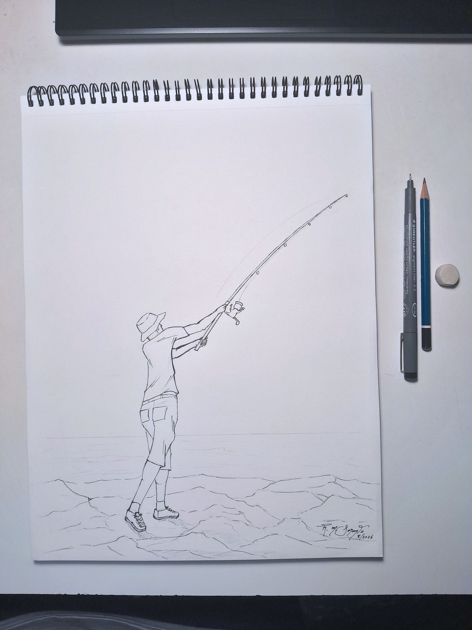 View of Fisherman No. 3 in a spiral-bound drawing pad on a work surface, accompanied by a technical pen, graphite pencil, and eraser.