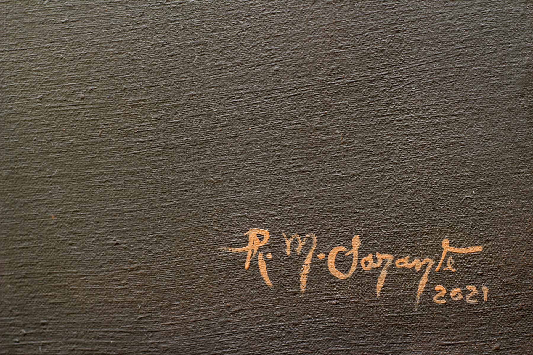 Artist's signature painted in warm ochre over a dark textured background in the lower corner of the canvas.