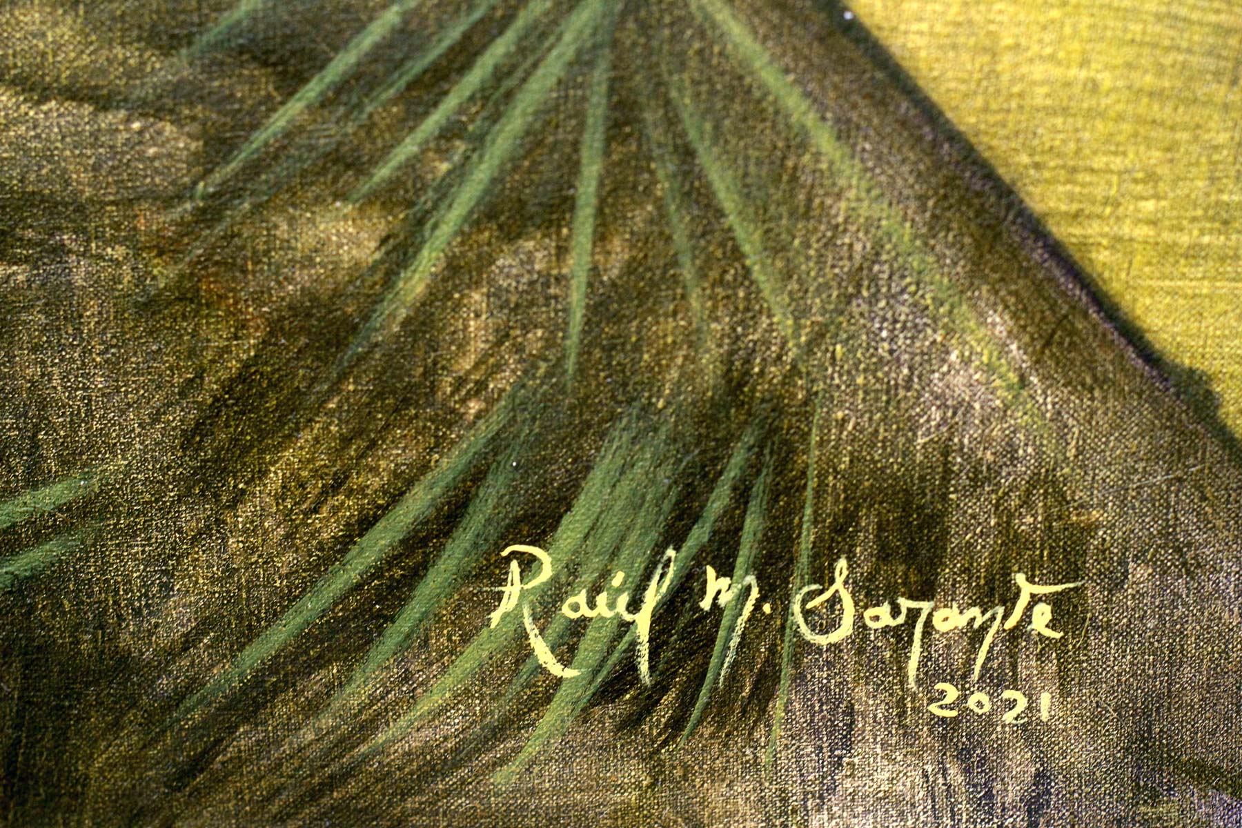 Close-up of the artist's signature painted in pale yellow over dark green foliage.