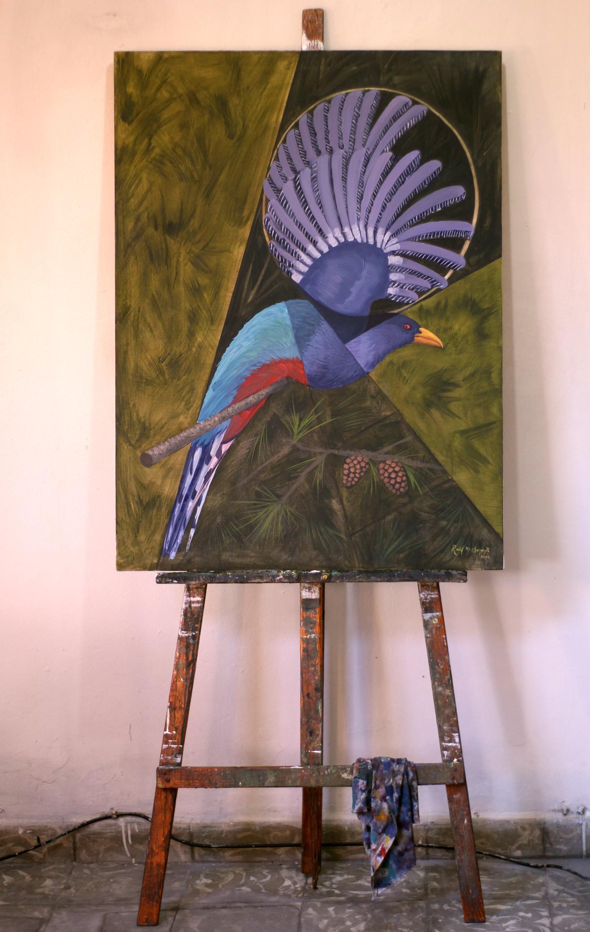 Hispaniolan Trogon displayed on a wooden studio easel, showing the complete oil painting of the endemic Caribbean bird perched on a pine branch with its lavender wings raised in a striking fan-like arrangement against a stylized geometric forest background.