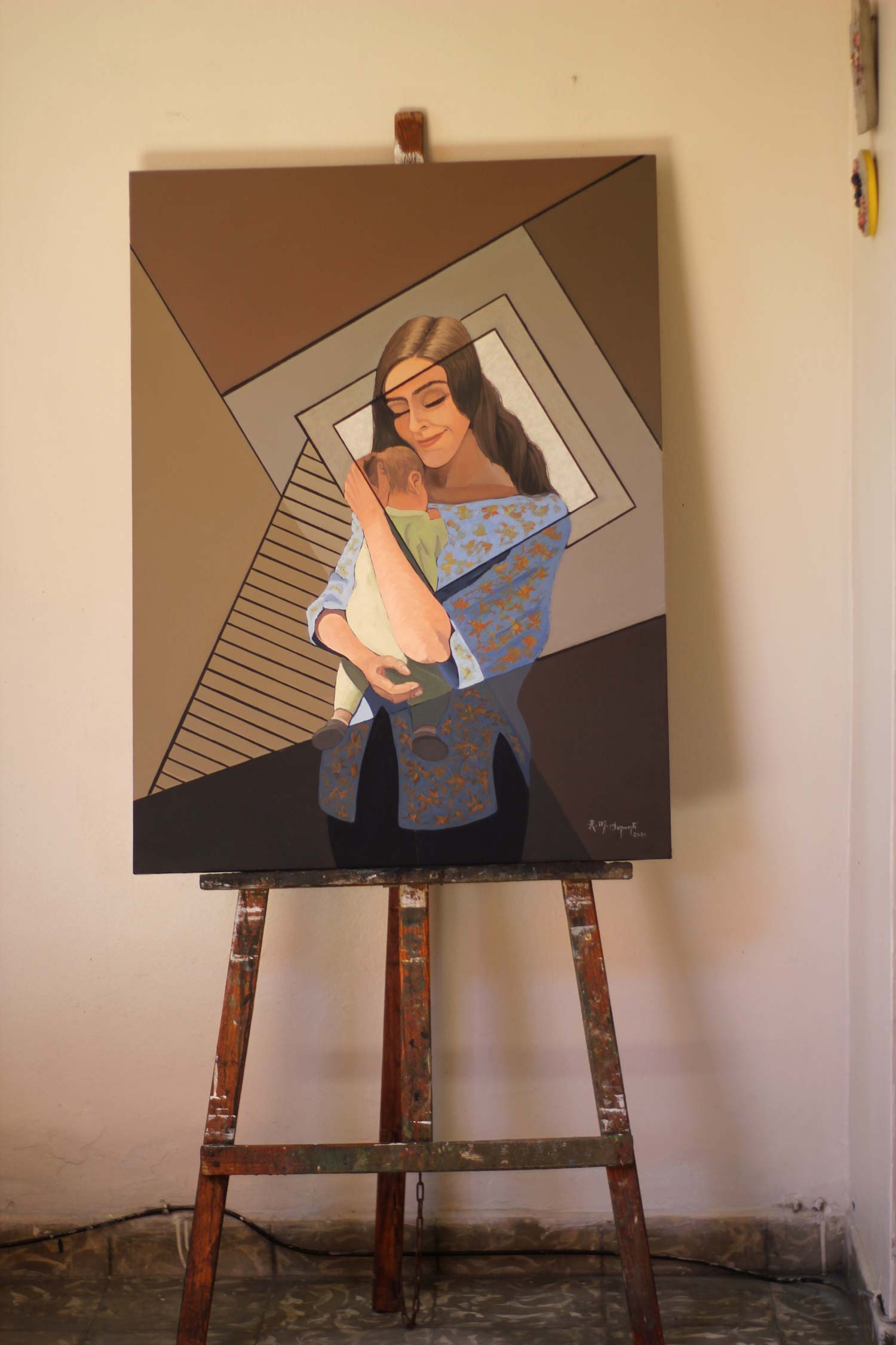 The completed oil painting "Maternity" displayed on a wooden studio easel, showing the full composition before exhibition.