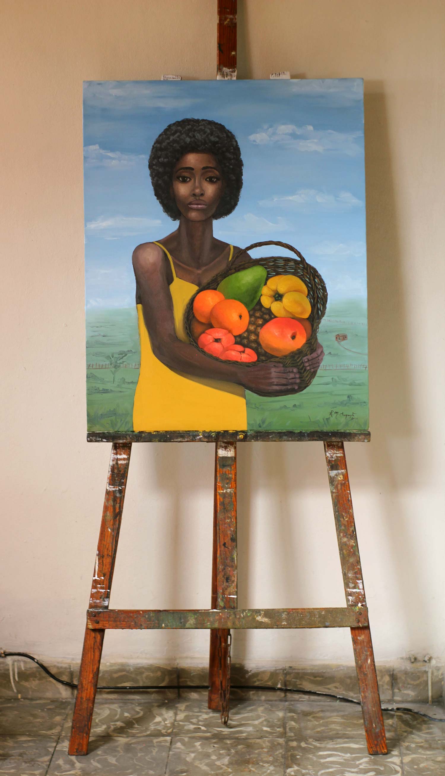 Woman with a Fruit Basket displayed on a wooden studio easel, showing the complete oil painting of a young Black woman in a yellow dress holding a woven basket filled with fruits.
